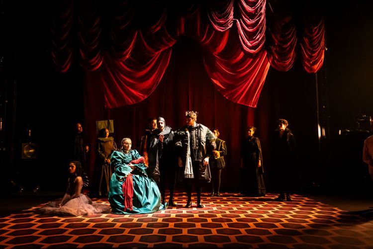 Cast of Henry VIII on stage in tudor style costumes with modern twists including a metal ruff